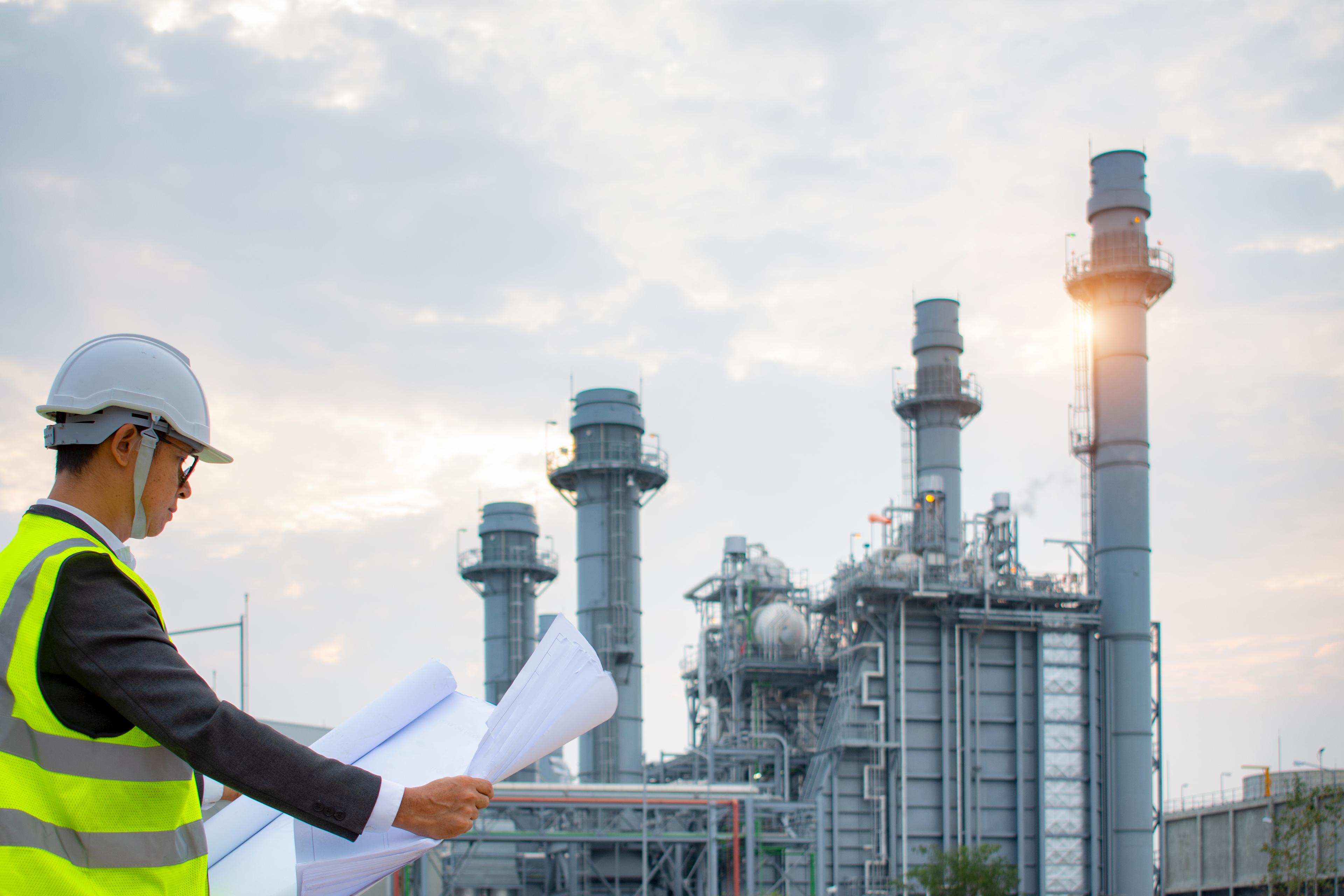 Ingenieros discutiendo el mantenimiento de una planta petroquímica y haciendo una inspección técnica.Engineers discussing maintenance of a petrochemical plant and doing technical inspection.