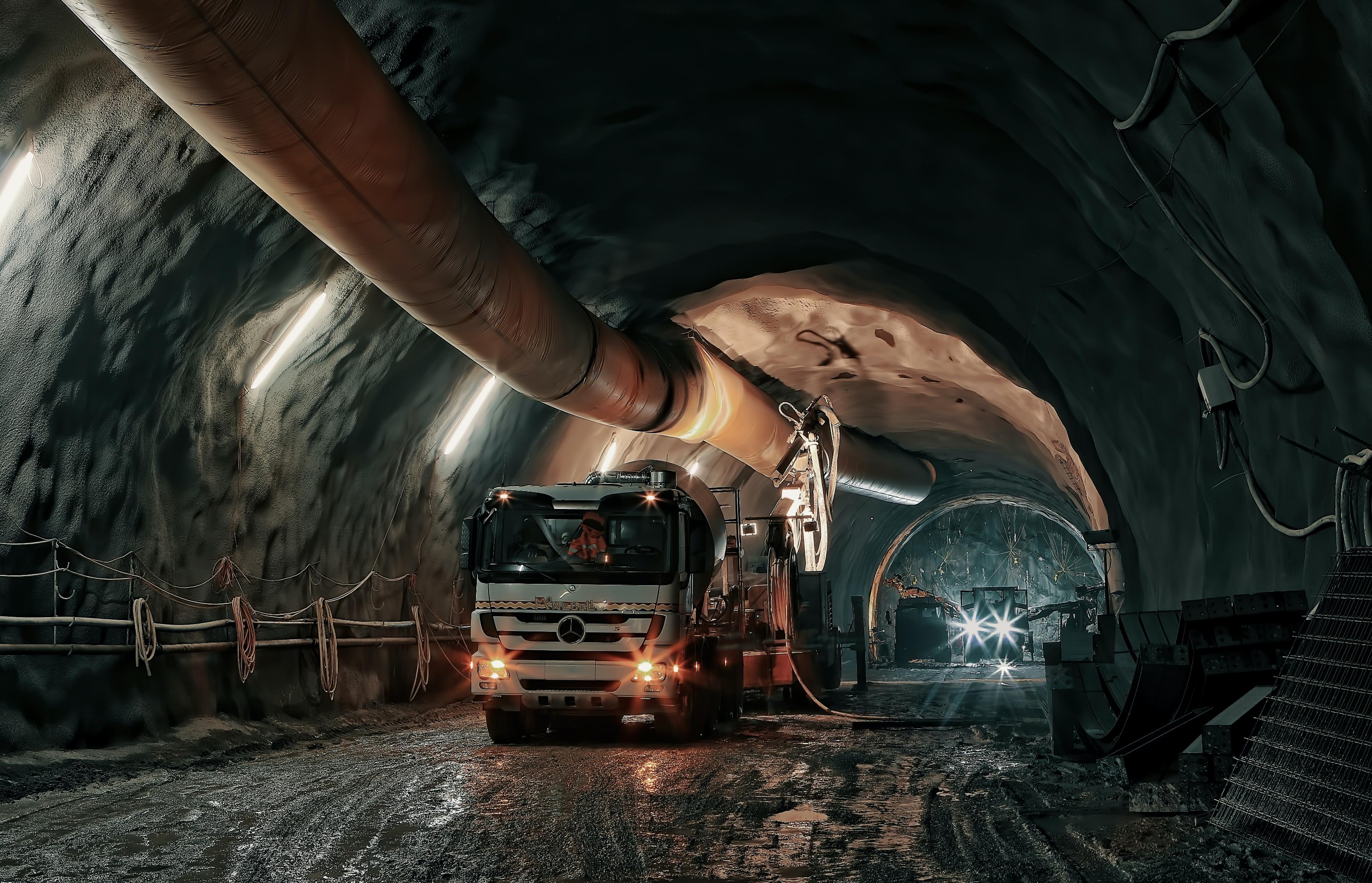 A truck packed in a mine with pipe running overhead.