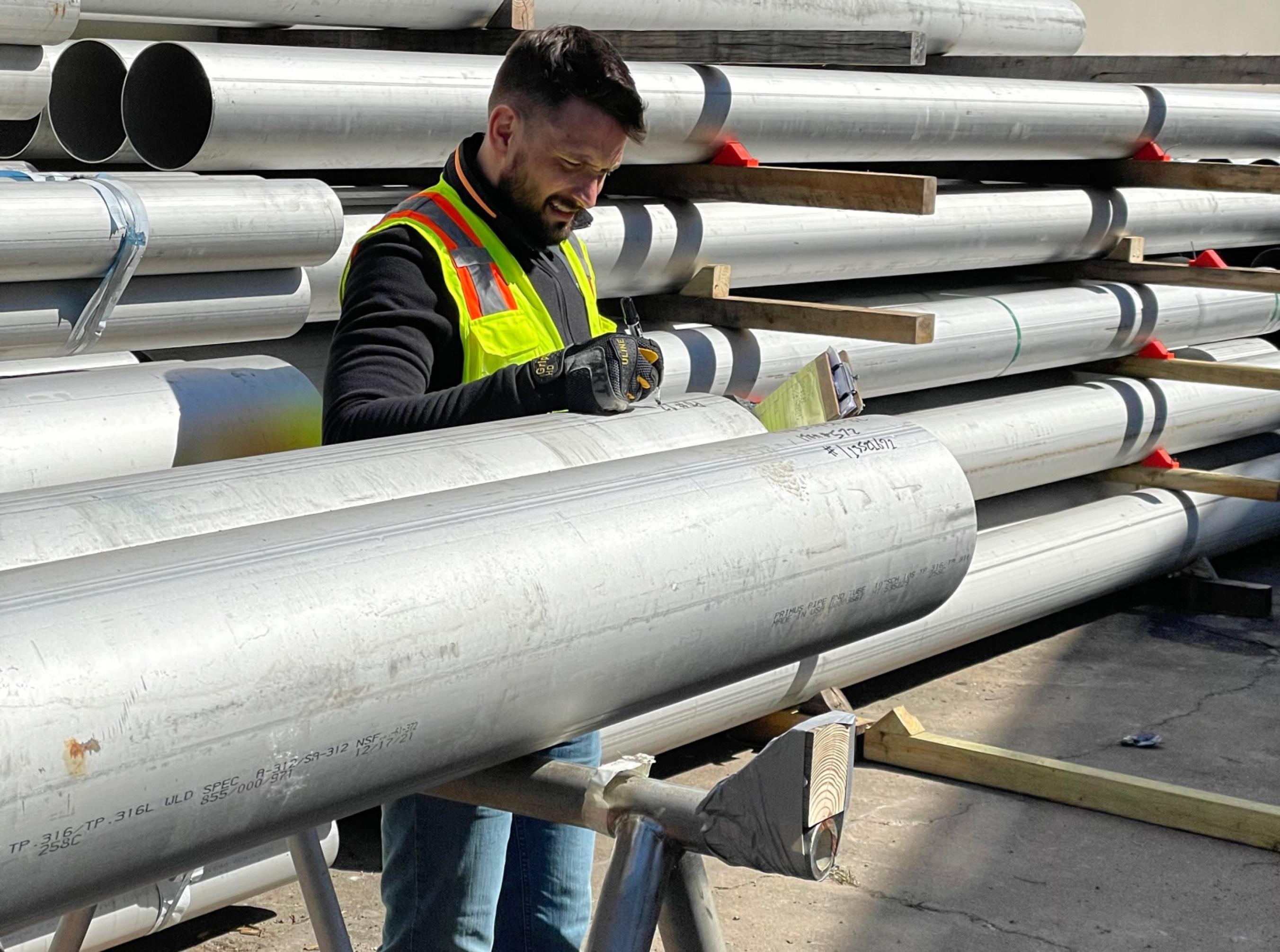 Male worker marking steel pipes